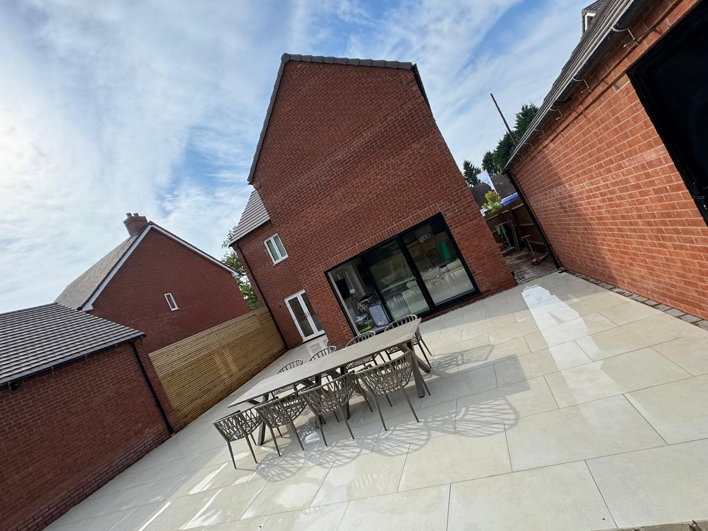 Large porcelain patio with outdoor dining table laid behind a new-build home in Warwickshire