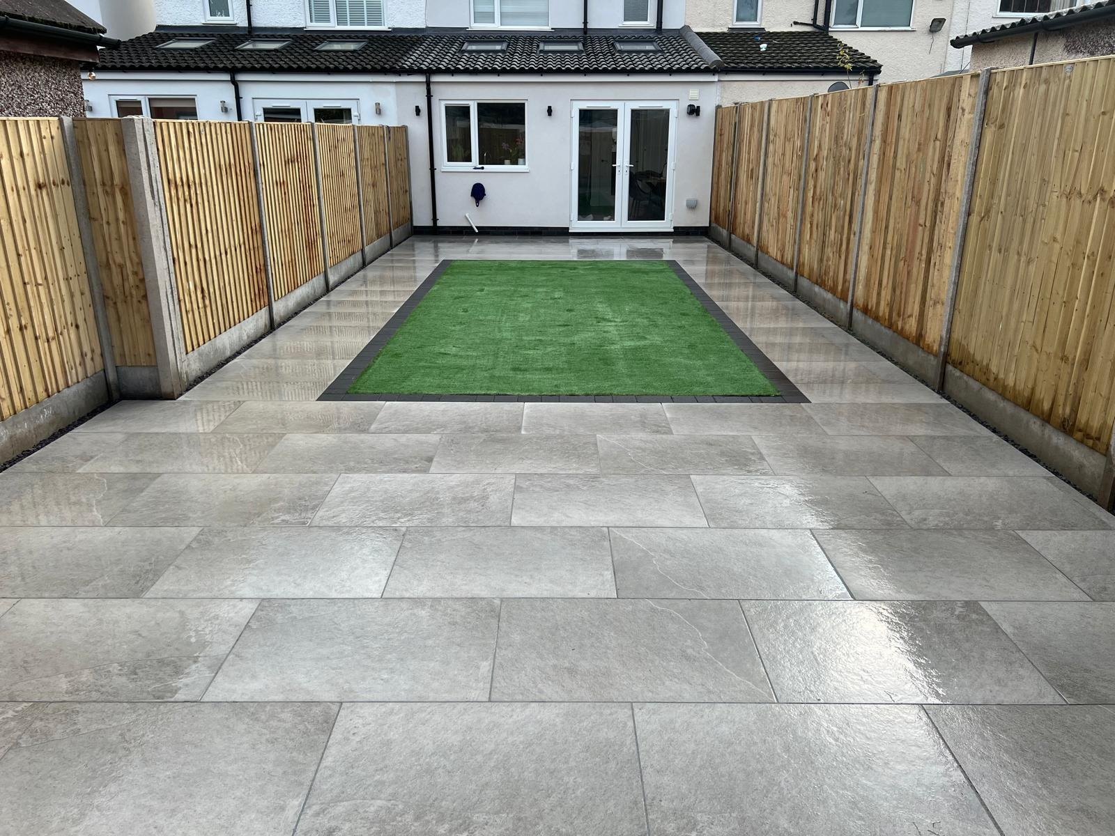Patios & paths by SOS Landscaping: Grey porcelain patio wrapping around a central lawn between new close-board fencing