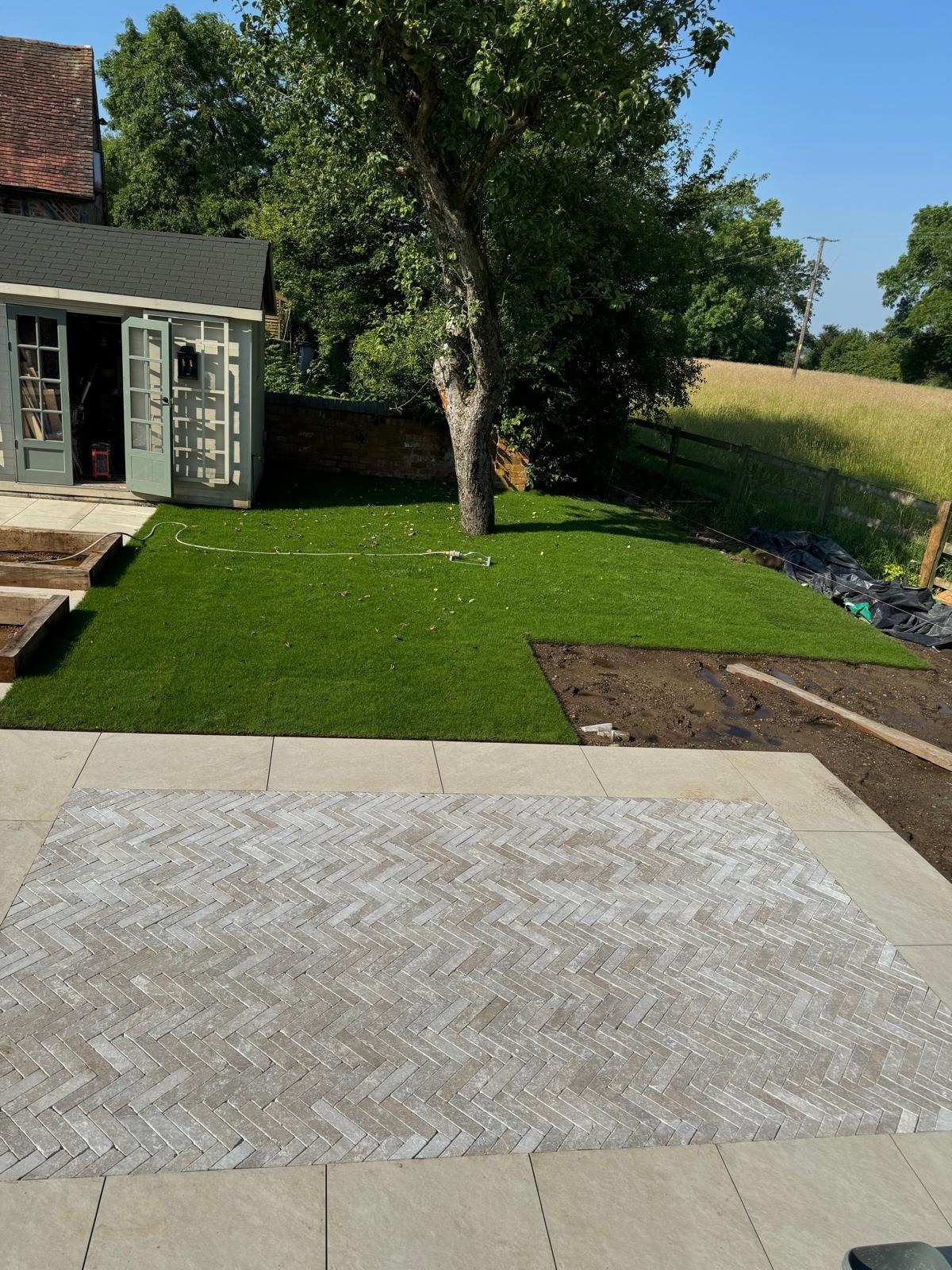 Turfing by SOS Landscaping: Freshly laid turf lawn beside a herringbone paved terrace in a country garden