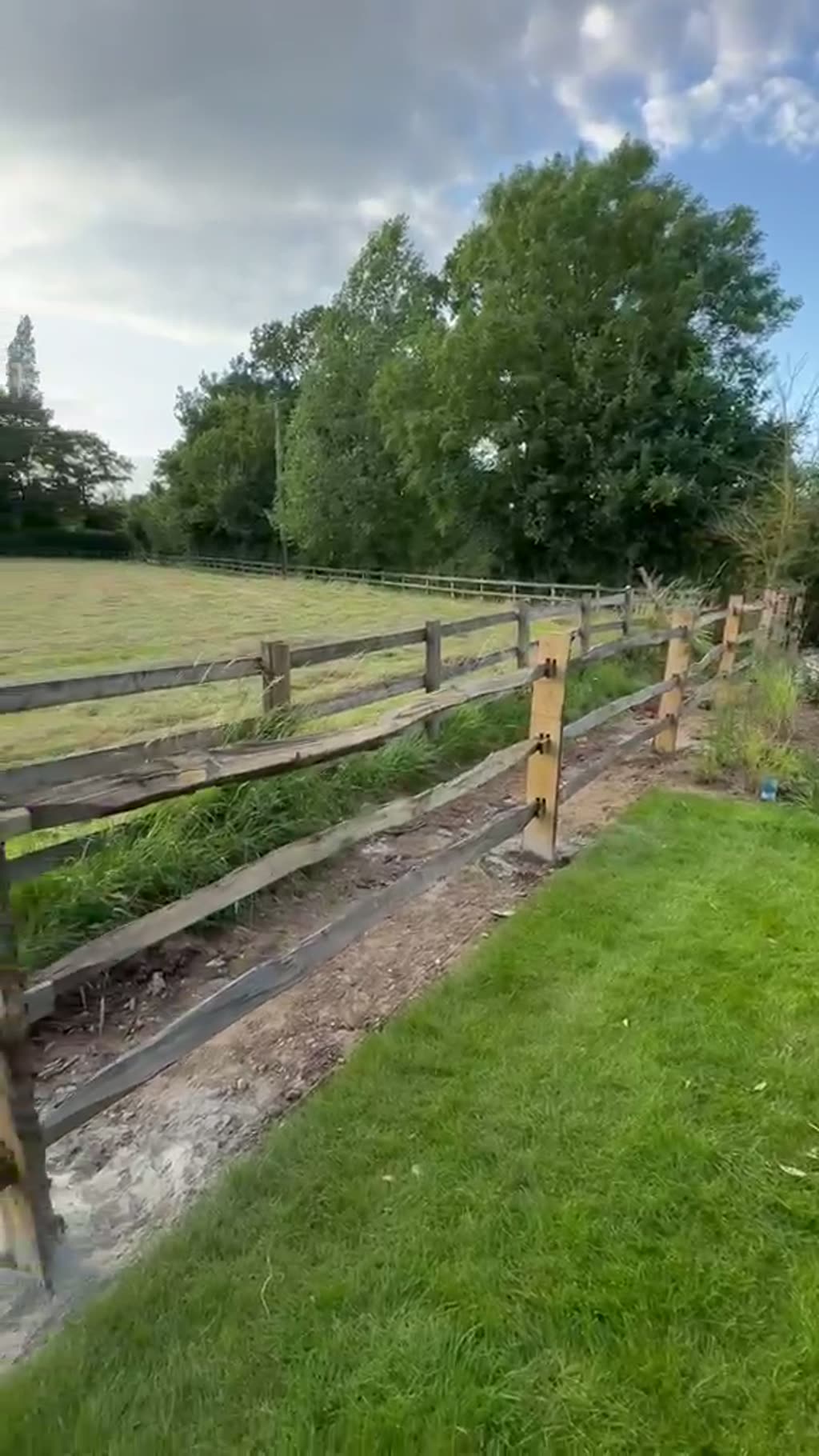 Walkthrough of a rural garden with post and rail fencing, lawn and newly planted border