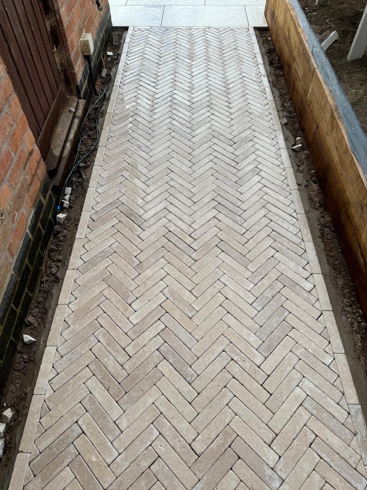 Block paving by SOS Landscaping: Herringbone block paved garden path with concrete edge restraints and sleeper border