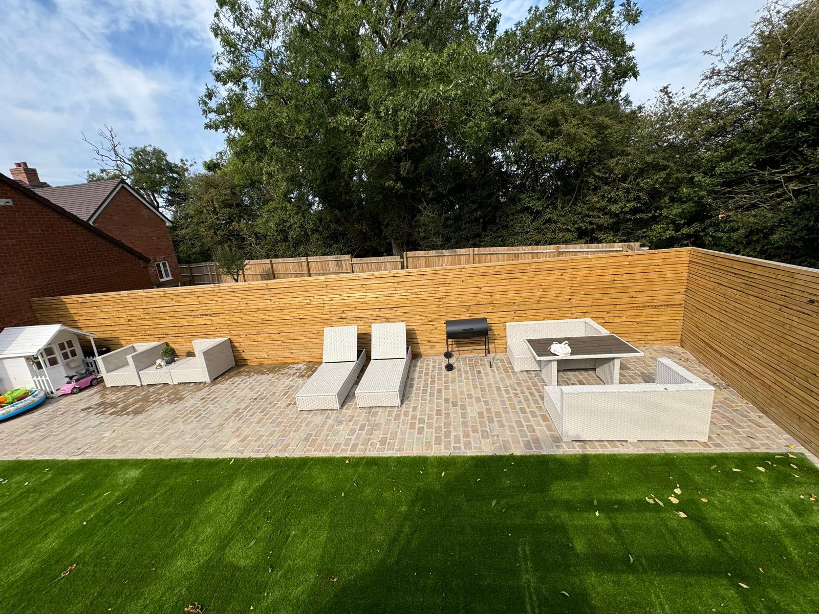 Completed family garden with cobbled seating area, lawn, planting and timber fencing